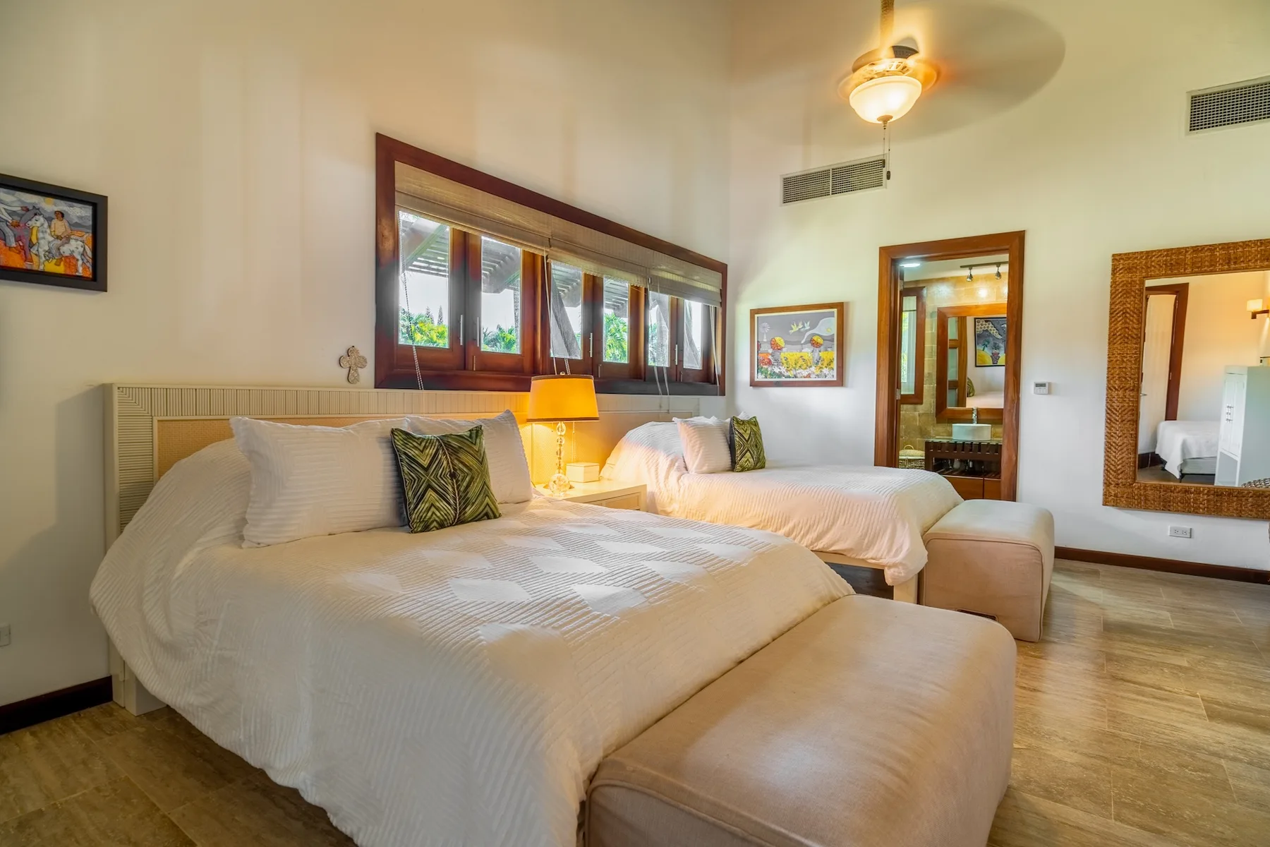 A bedroom with two beds, warm lighting, and windows along the wall.