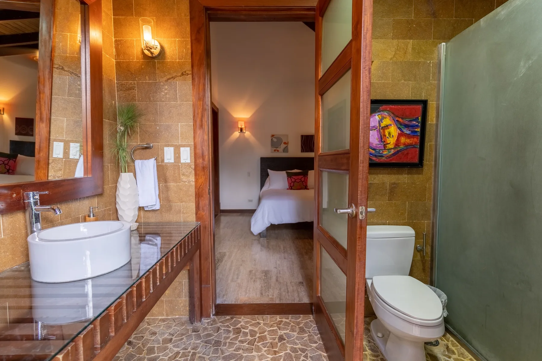 A bathroom opens onto a bedroom, with a sink and toilet visible.