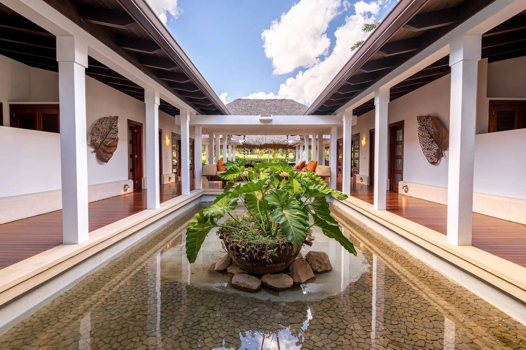 An open-air courtyard with a central reflecting pool and tropical plants.