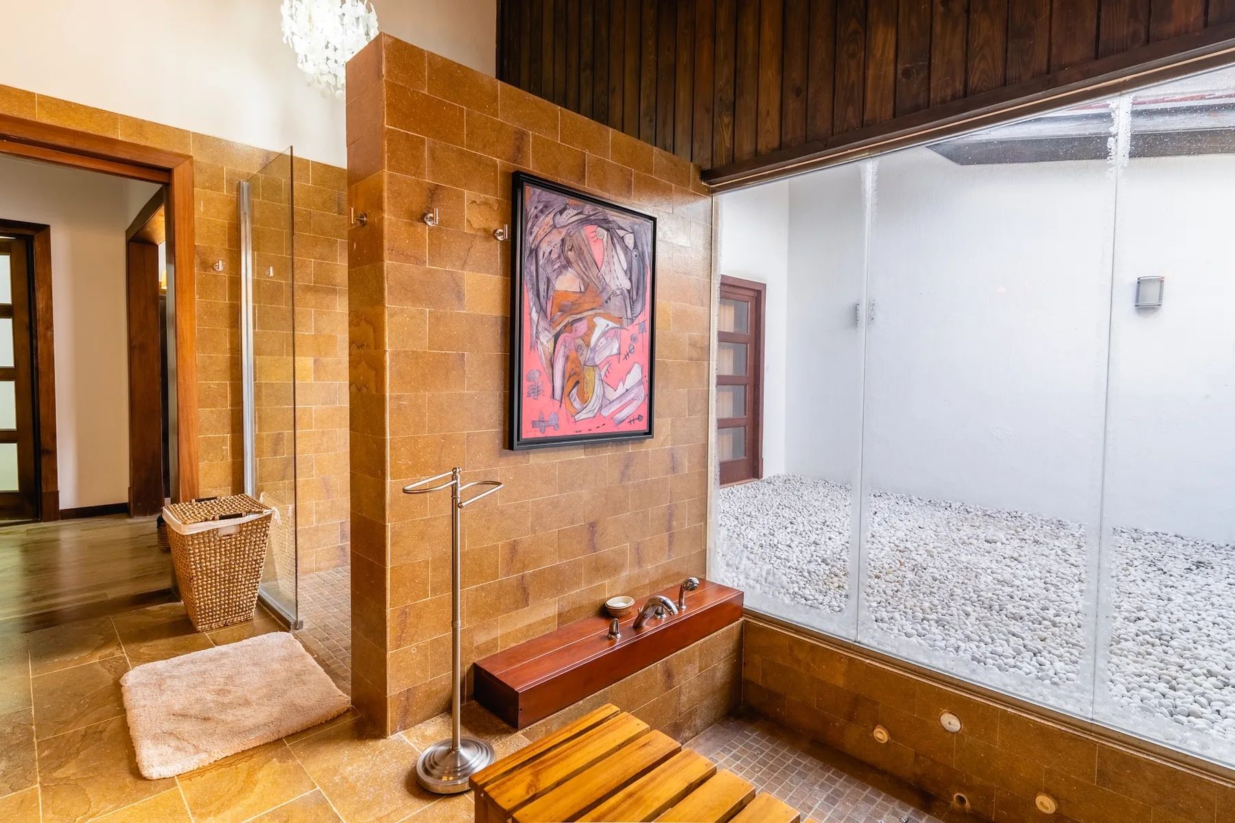 A bathroom with a glass-enclosed shower and a framed artwork on the tiled wall.