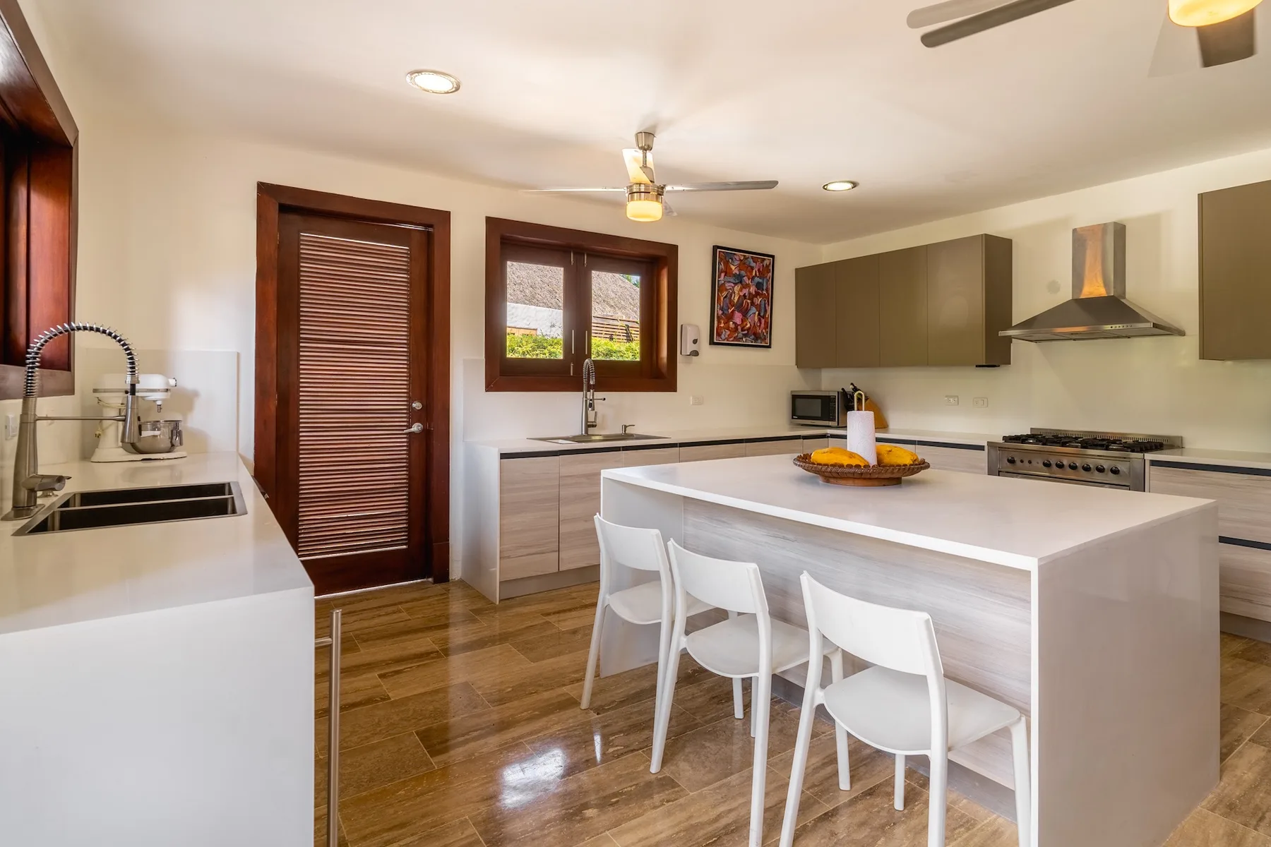 A bright kitchen with a central island and white seating.