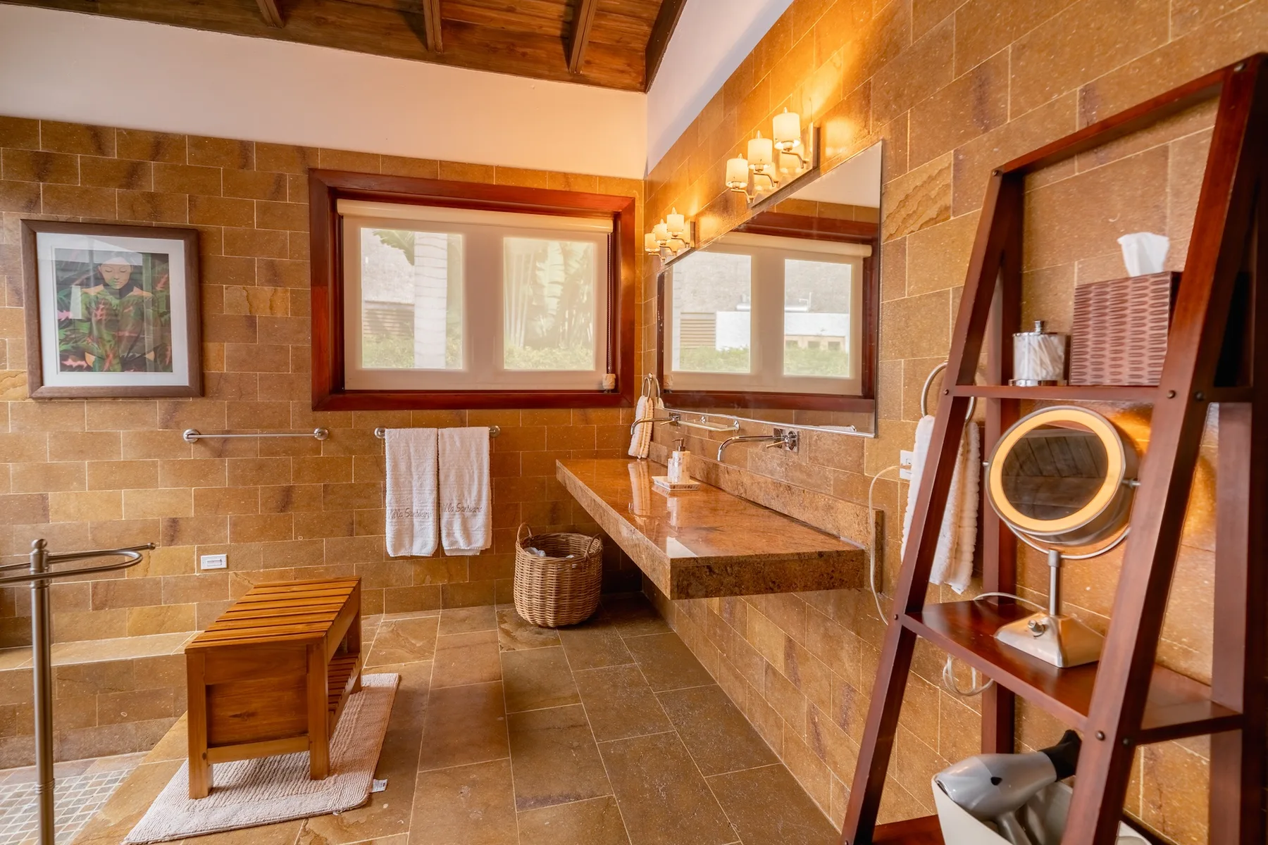 A tiled bathroom with a vanity, mirrors, and a wooden ceiling.
