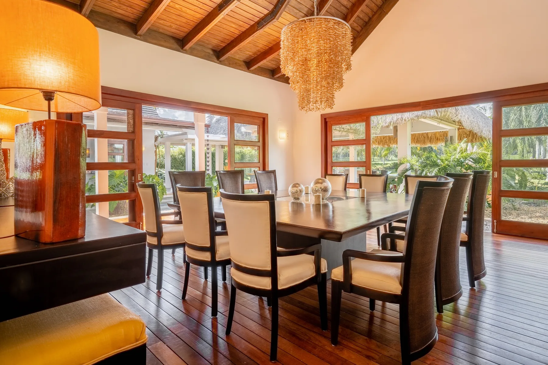 A dining room with a long table and seating beneath a wood-beamed ceiling.