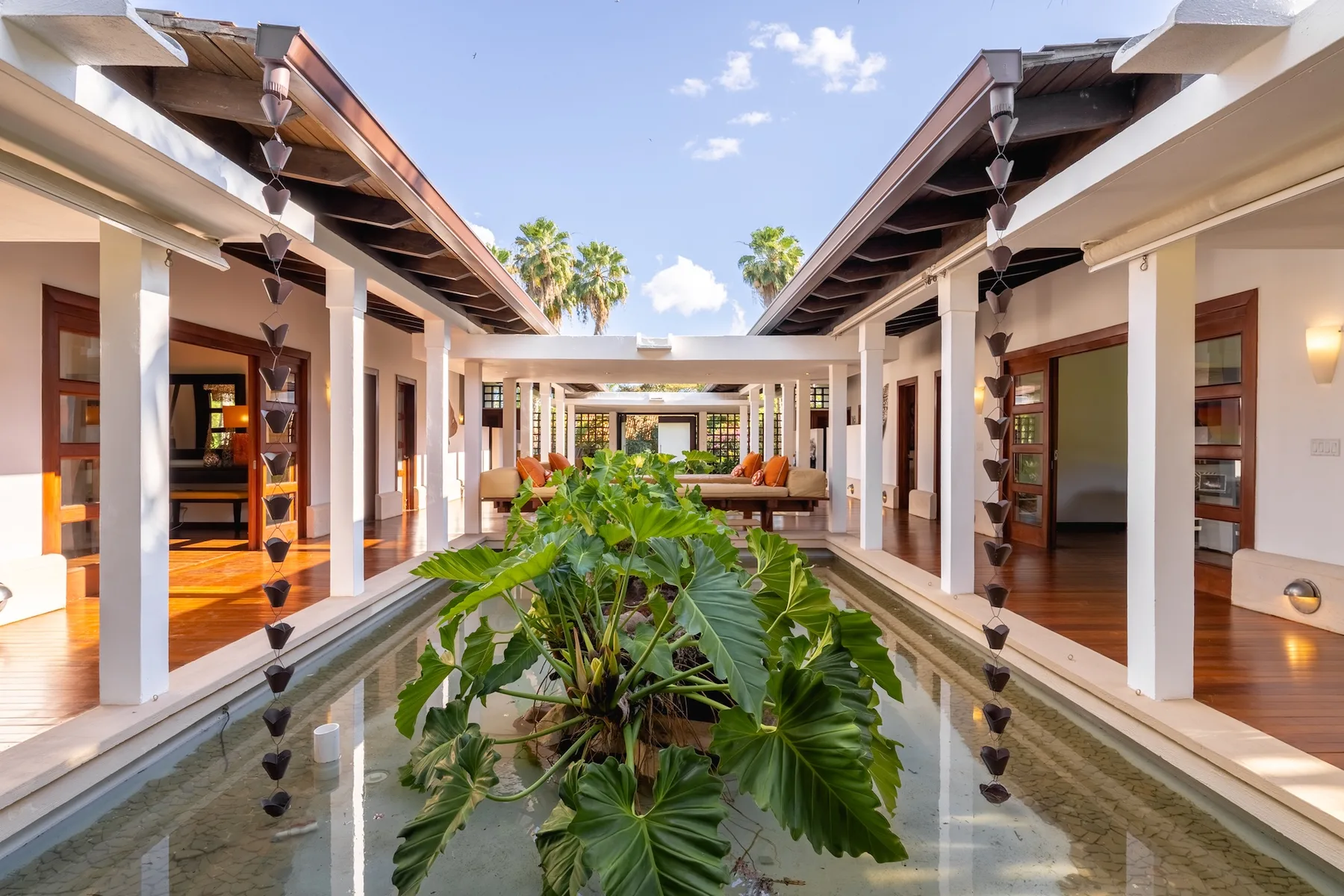 An open courtyard with a long reflecting pool, tropical plants, and seating.