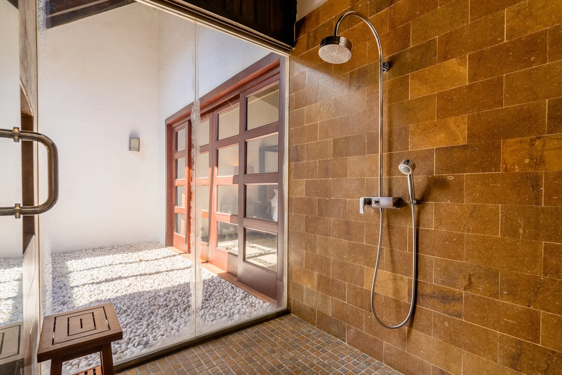 A tiled shower area opens onto a bright patio through glass doors.