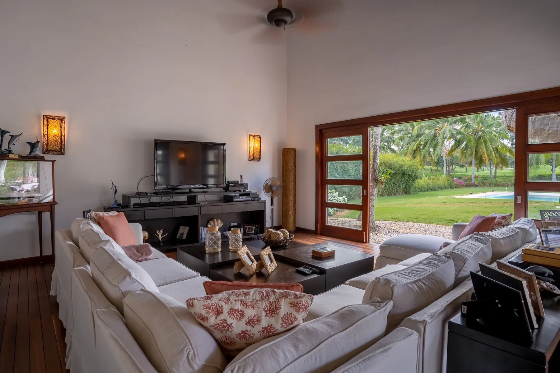 A living room with seating arranged around a coffee table and a garden view.