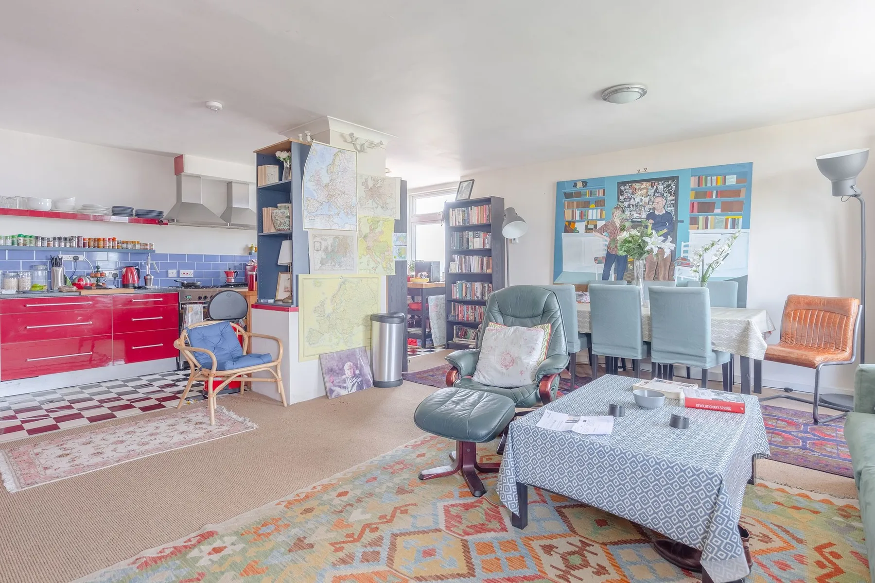 A bright open room combines a dining area with a kitchen and seating.