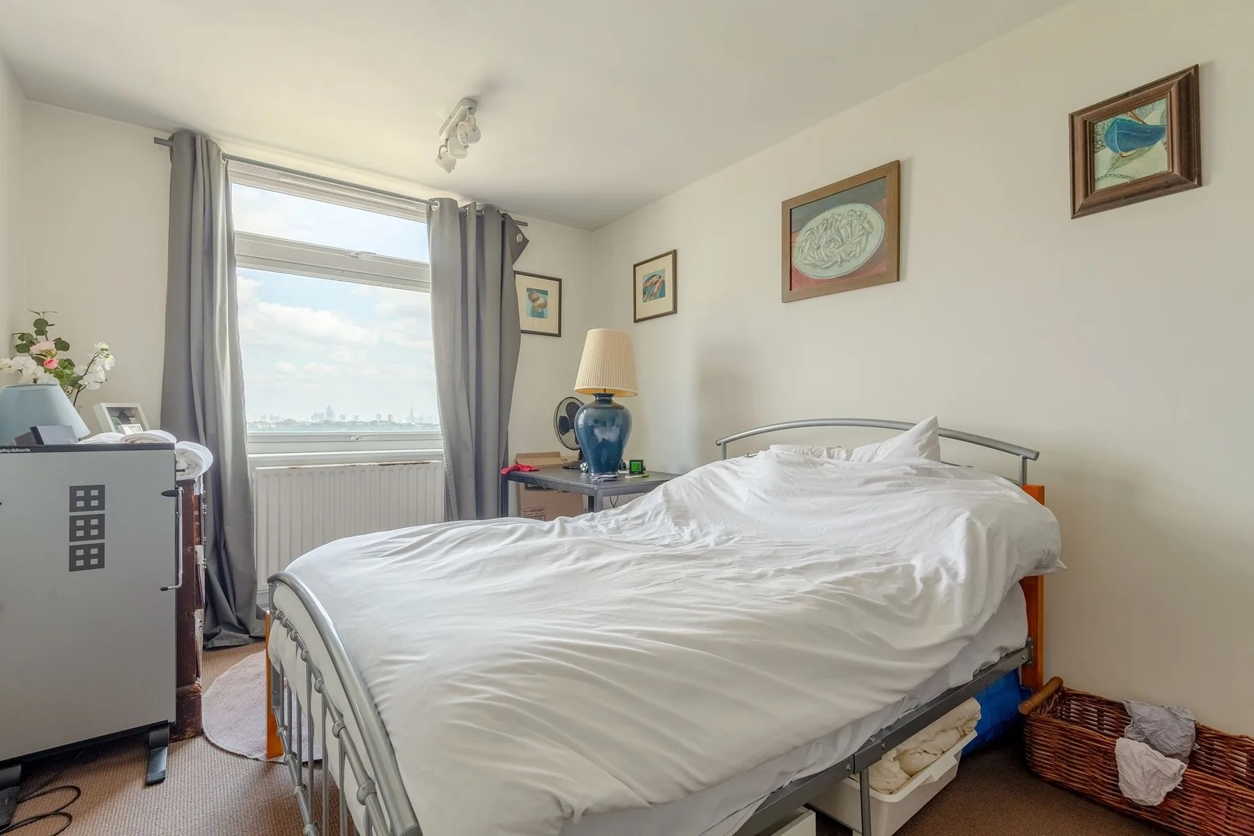 A bedroom with a bed beside a window with curtains.