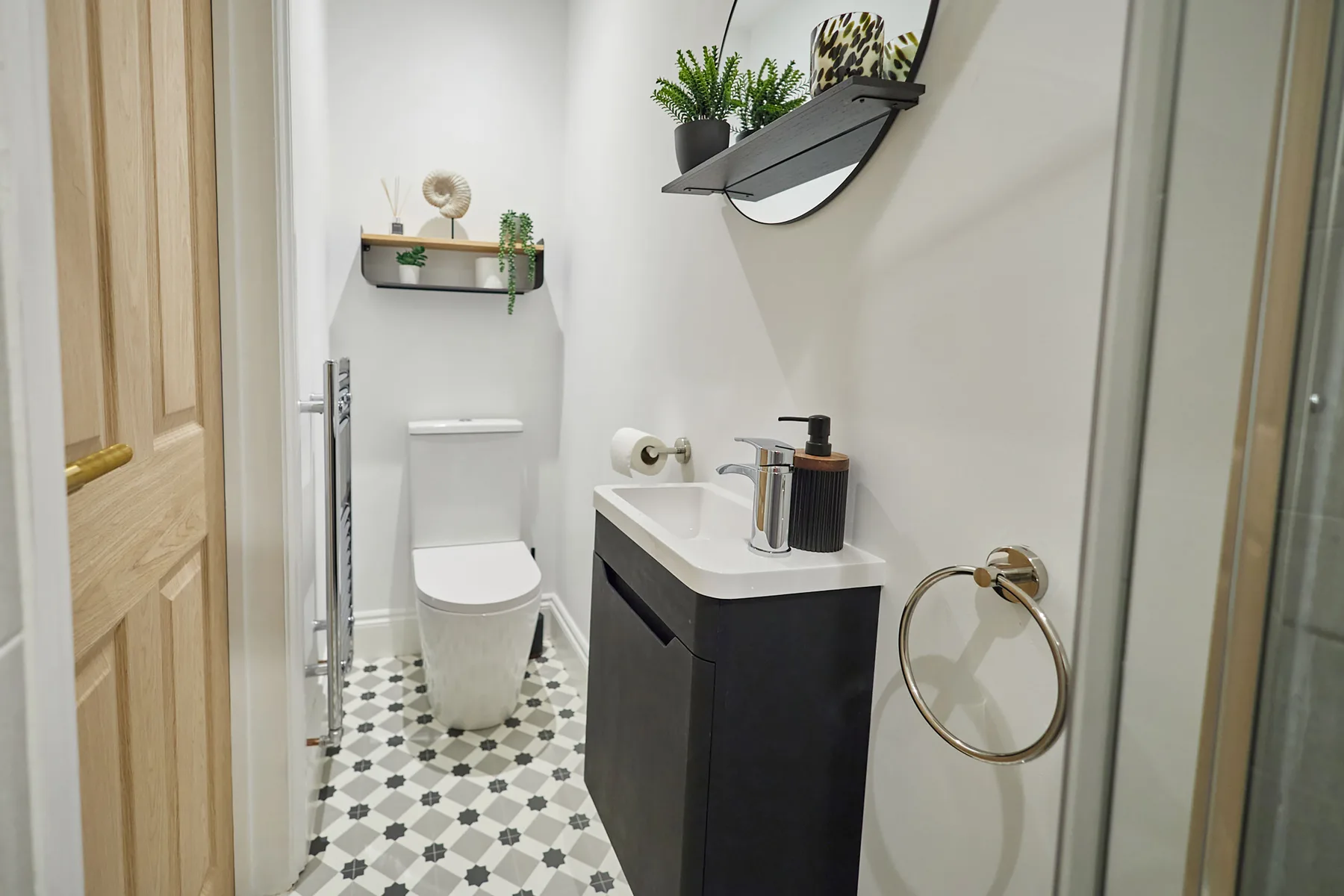 Un baño compacto con lavabo, inodoro y suelo de baldosas estampadas.