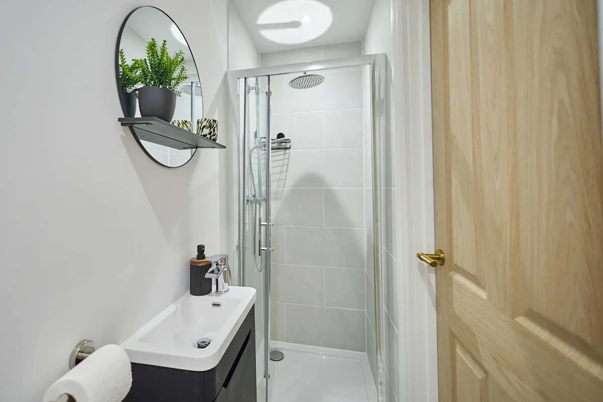 Baño con una ducha de vidrio y un lavabo debajo de un espejo de pared.