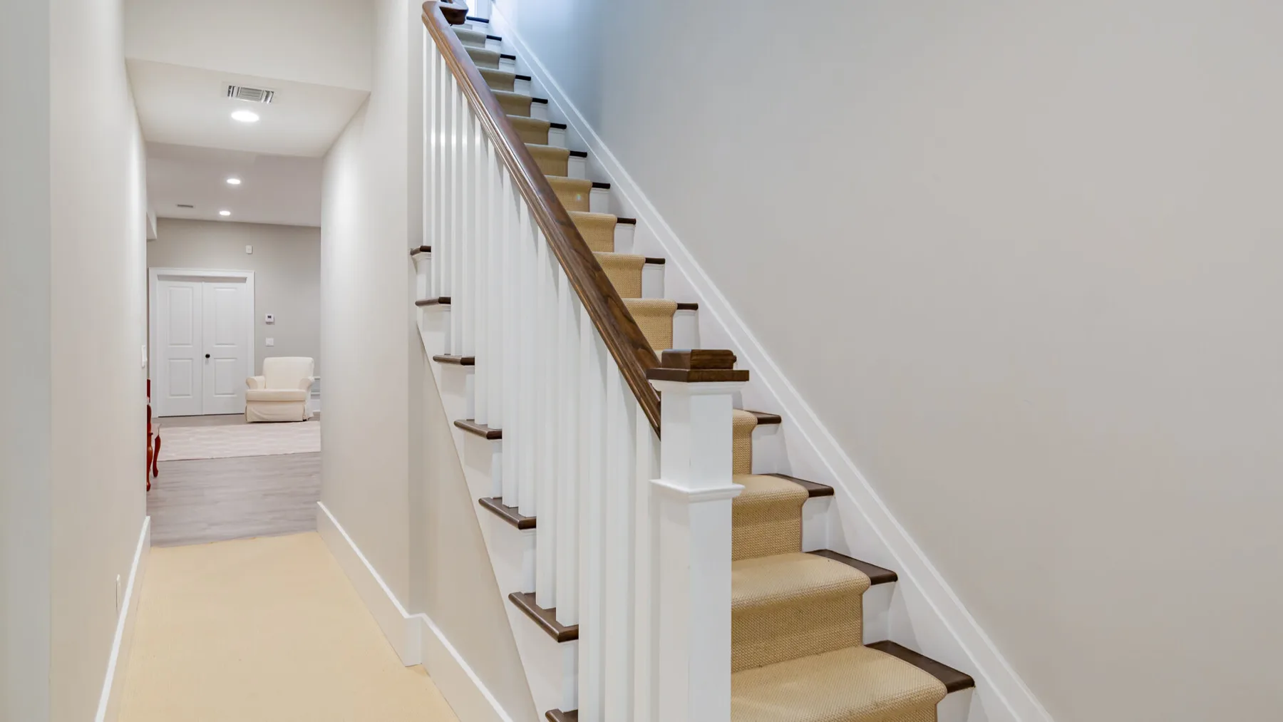 A bright hallway with a staircase and a closed door at the far end.