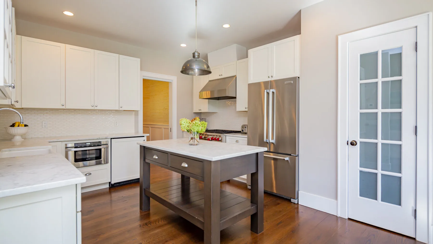 A bright kitchen with white cabinets and a central island.