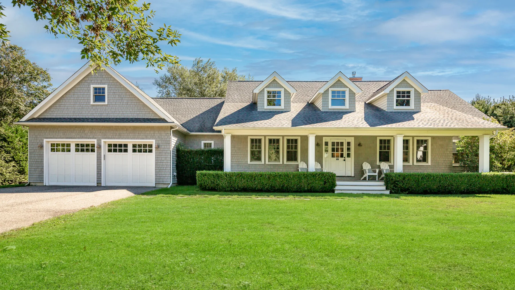 A large house with an attached garage, front lawn, and covered porch.