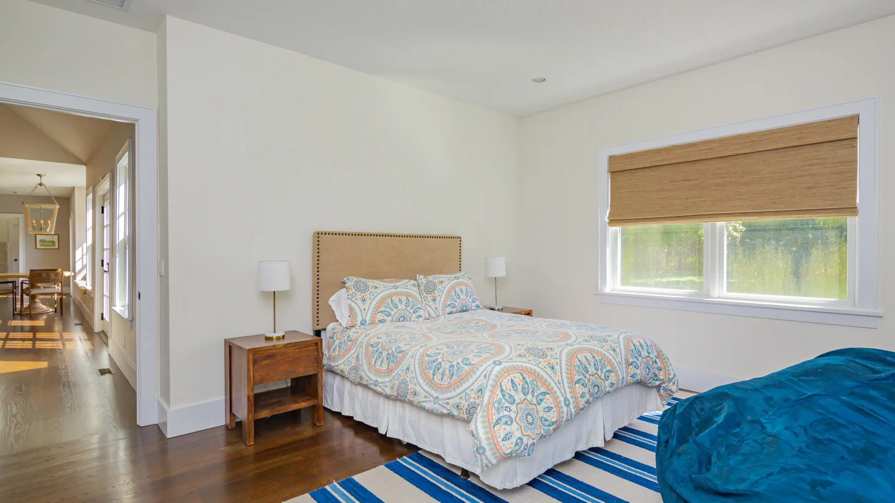 A bedroom with a patterned bed, bedside table, and window.