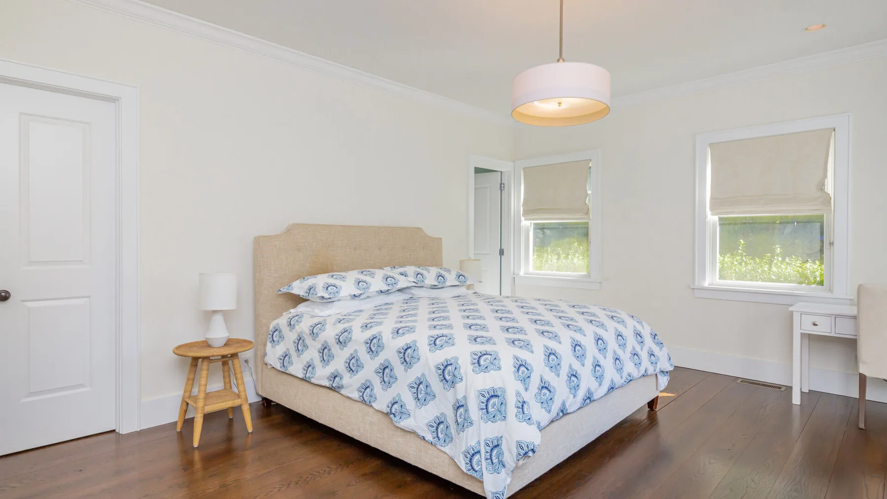 A bright bedroom with a bed dressed in blue-and-white patterned bedding.