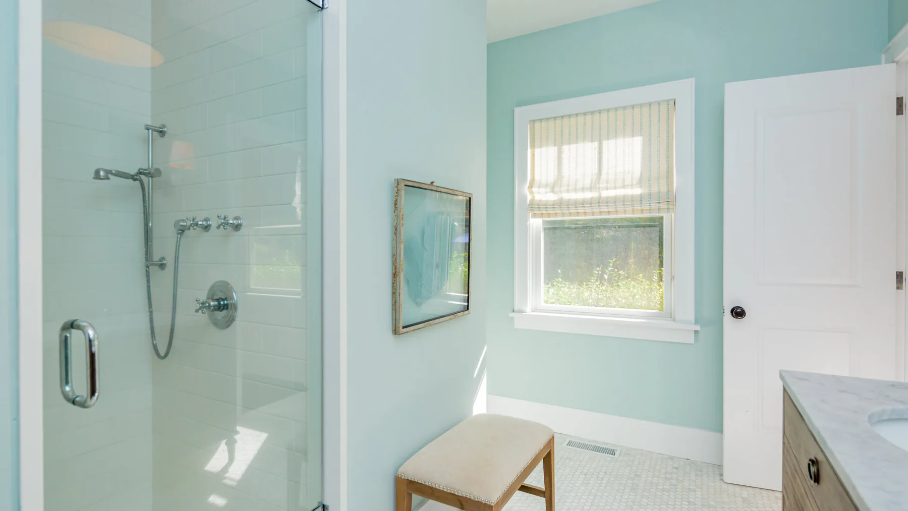 A bright bathroom with a glass shower and a window.