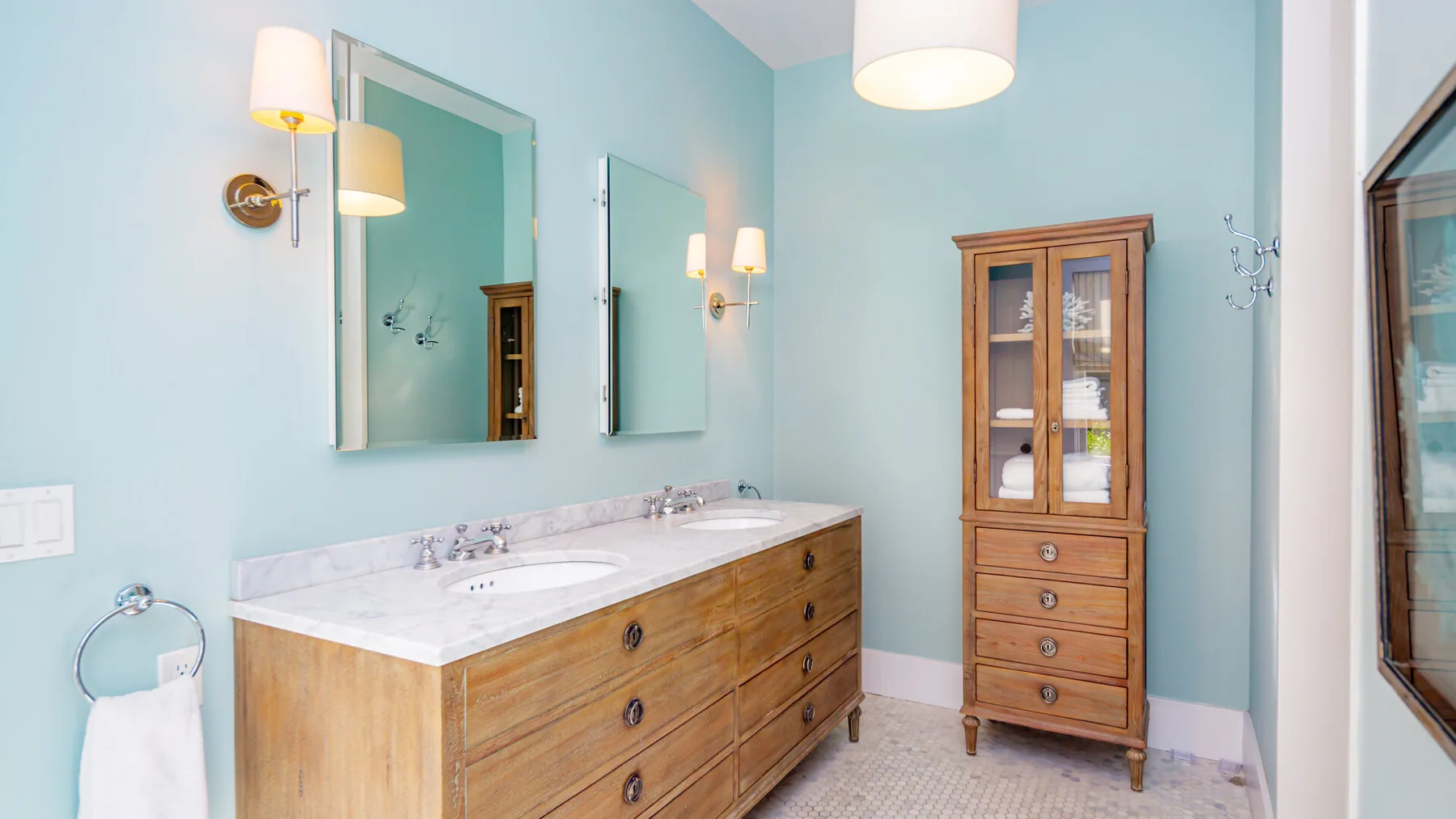 A bathroom vanity with a wide mirror and a wooden cabinet.
