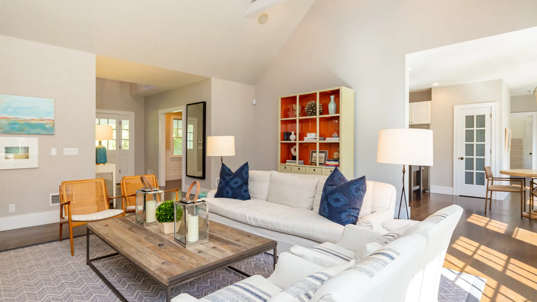 A bright living room with white seating and a wooden coffee table.