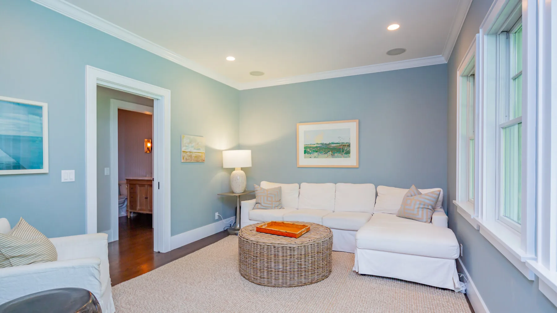 A bright living room with a pale sectional and round coffee table.