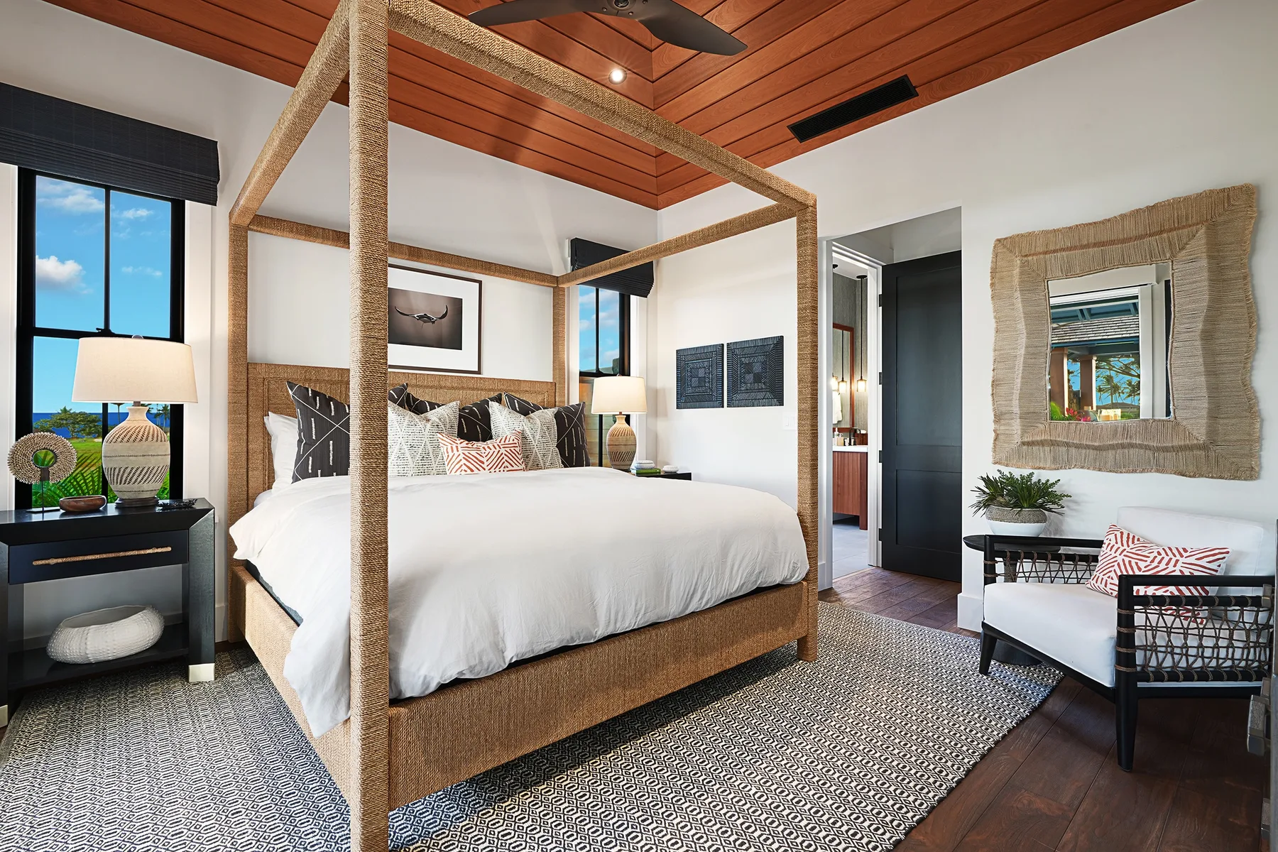 A bedroom with a large canopy bed, a window, and a seating area.