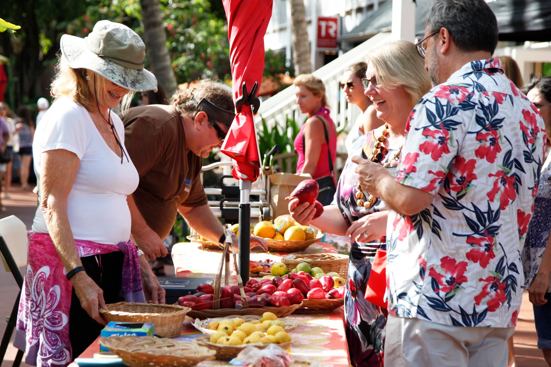 People browse fresh fruit at an outdoor market stall.