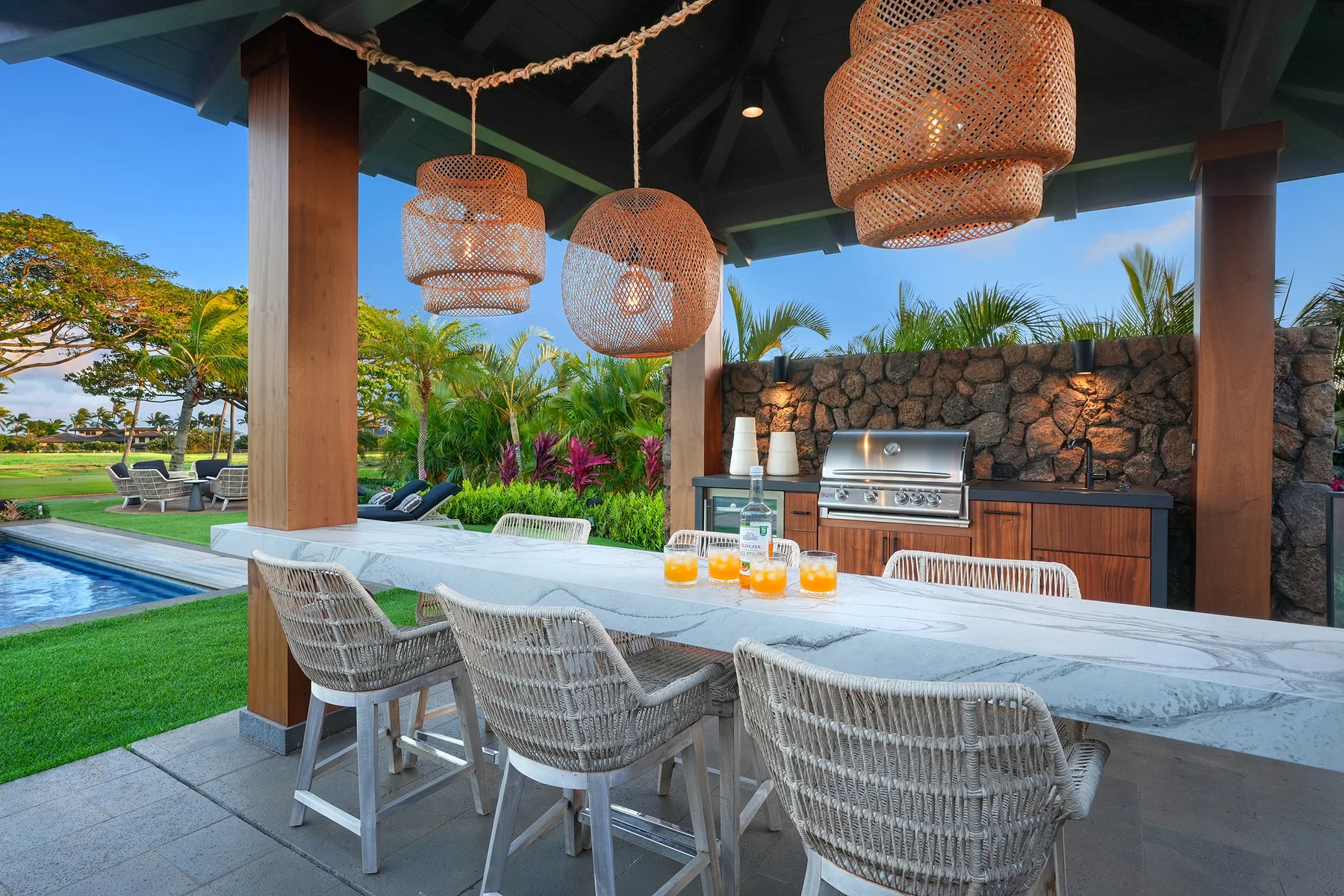 An outdoor dining area with woven seating and a built-in grill.