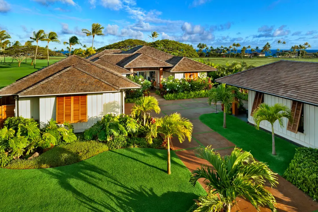 A tropical resort complex surrounds a paved walkway with green lawns and palm trees.