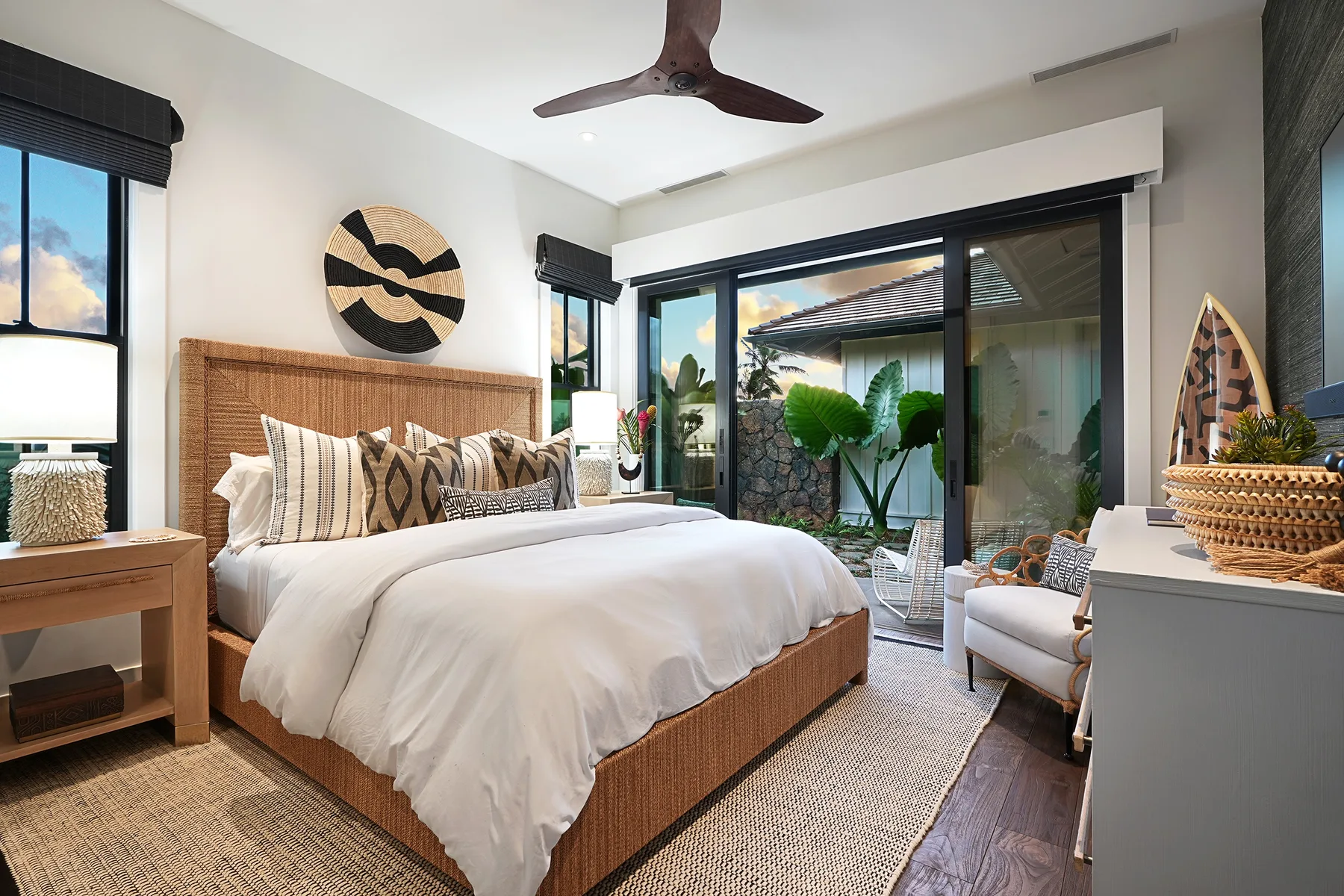 A bright bedroom with a bed beside large glass doors opening onto a garden.