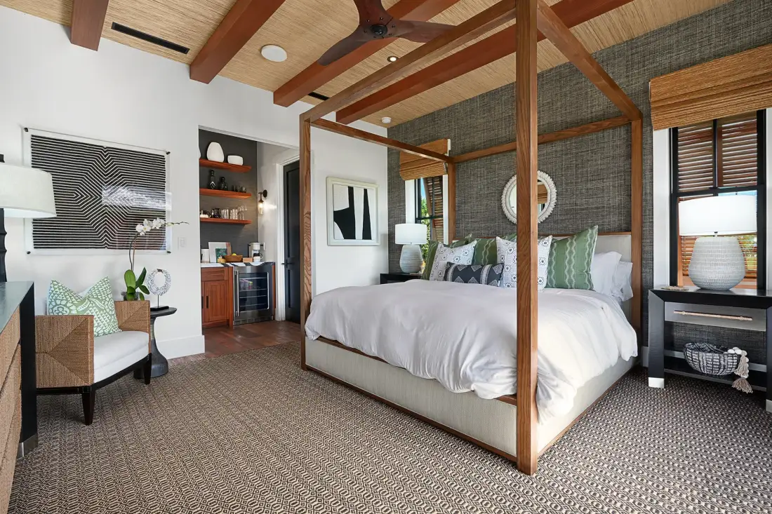 A bedroom with a large bed, patterned rug, and exposed wooden ceiling beams.