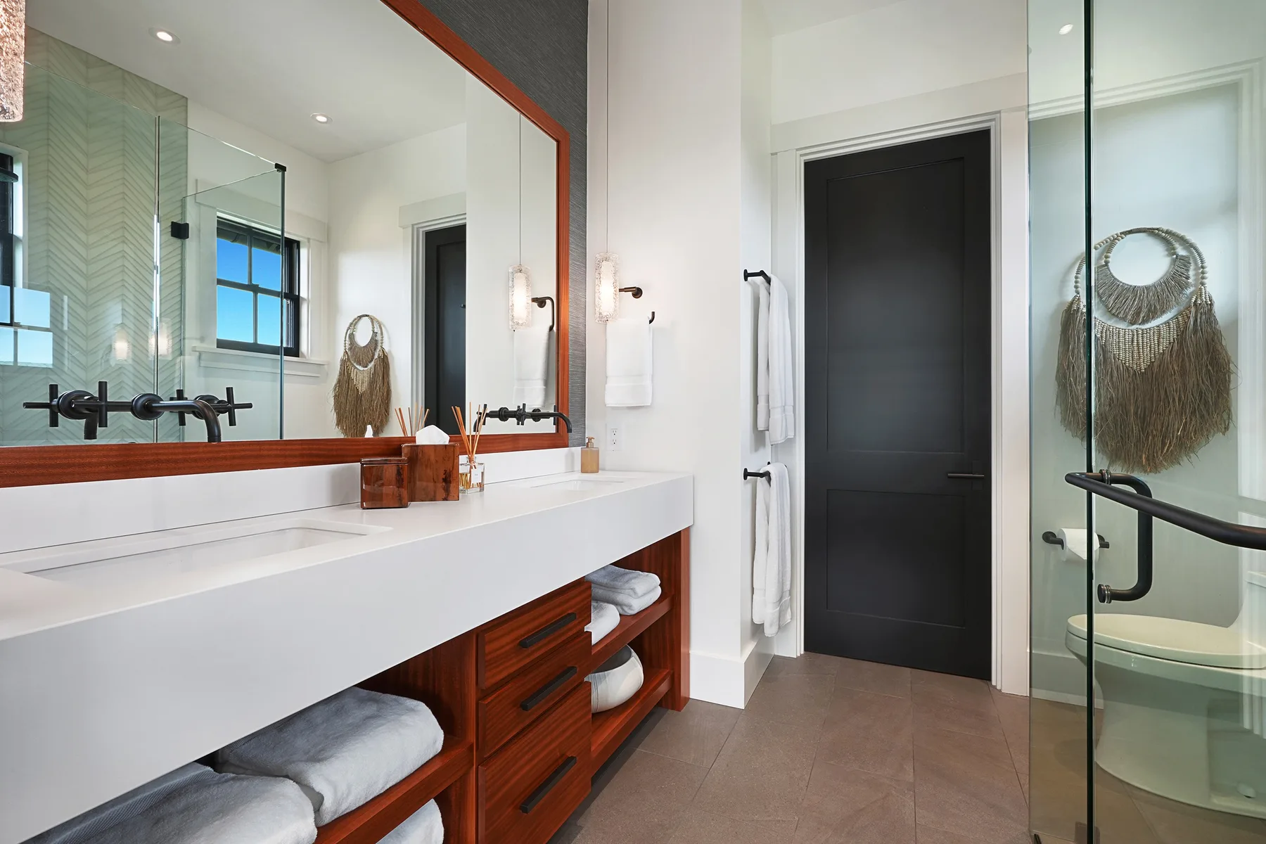 A bright bathroom with a long vanity, large mirror, and glass shower.
