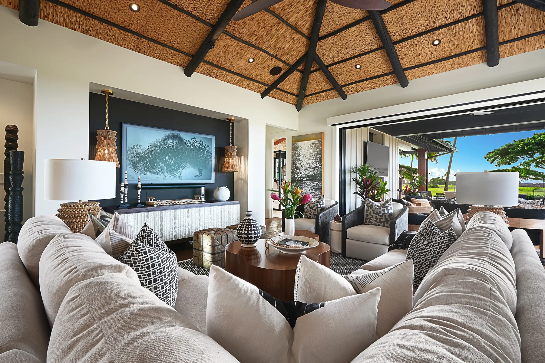 A bright living room with plush seating, a coffee table, and a large screen.