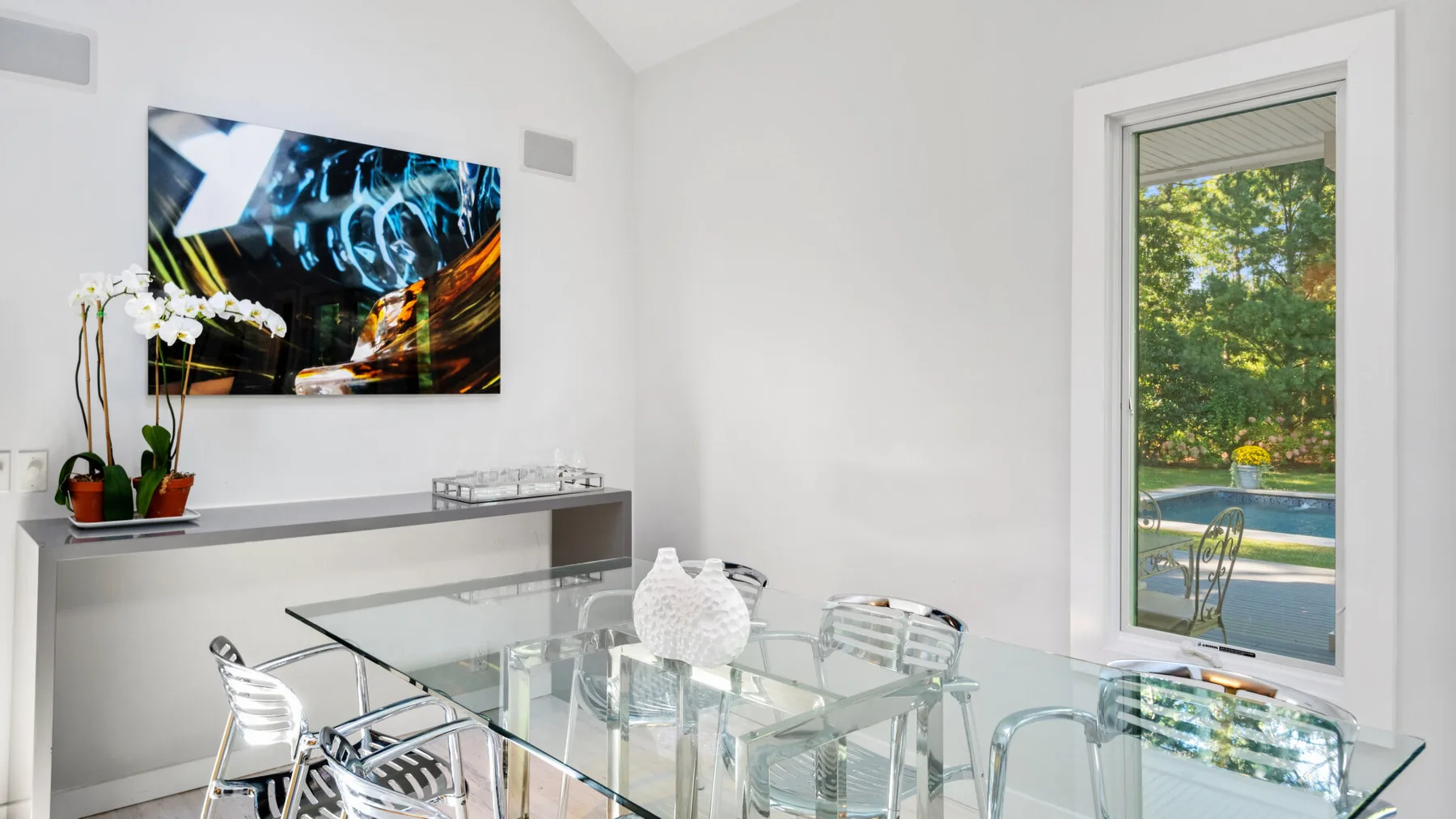 Un comedor luminoso con una mesa de cristal y una obra abstracta en la pared.
