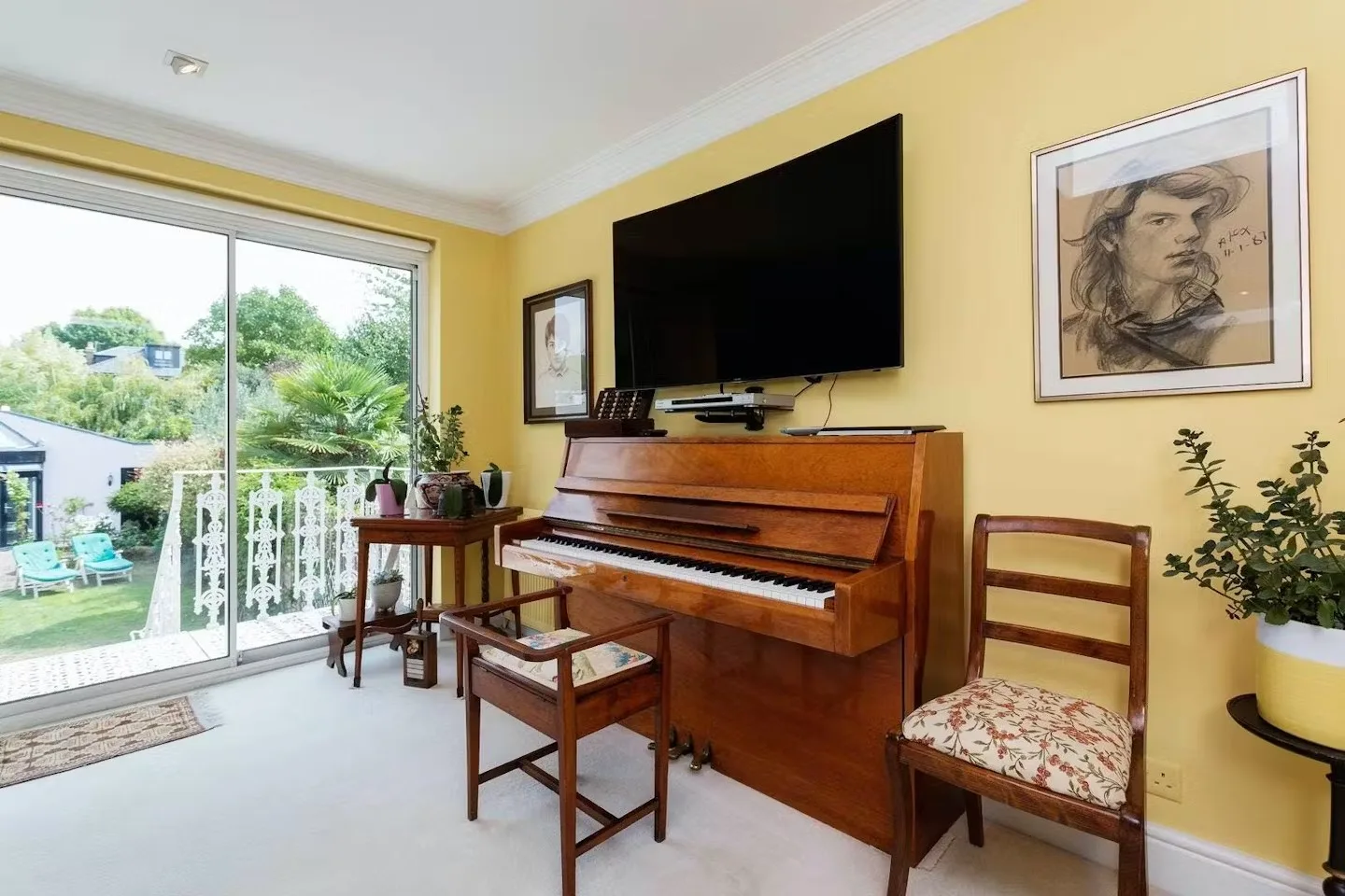 A living room with a piano beneath a wall-mounted television and a glass door to the garden.