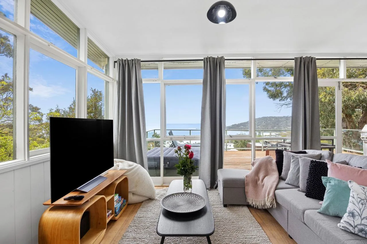 La sala de estar tiene asientos frente a grandes ventanas con vistas al agua.