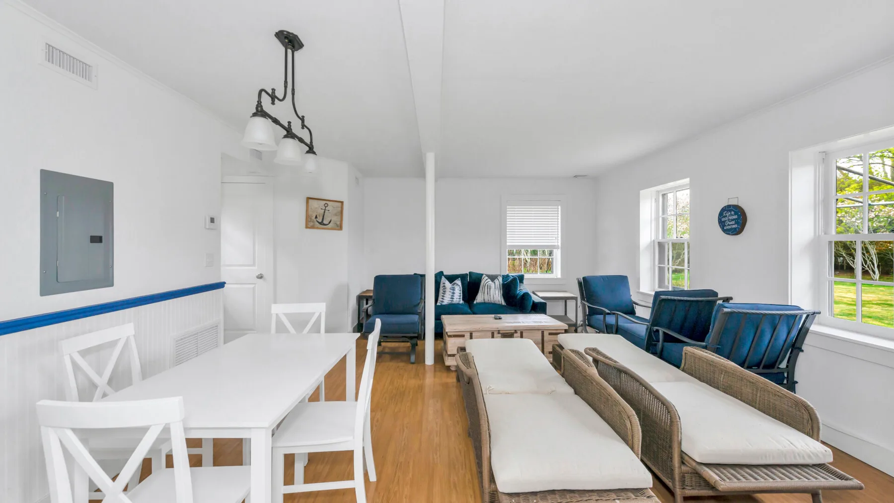 Una sala luminosa con asientos alrededor de una mesa de centro y ventanas grandes.
