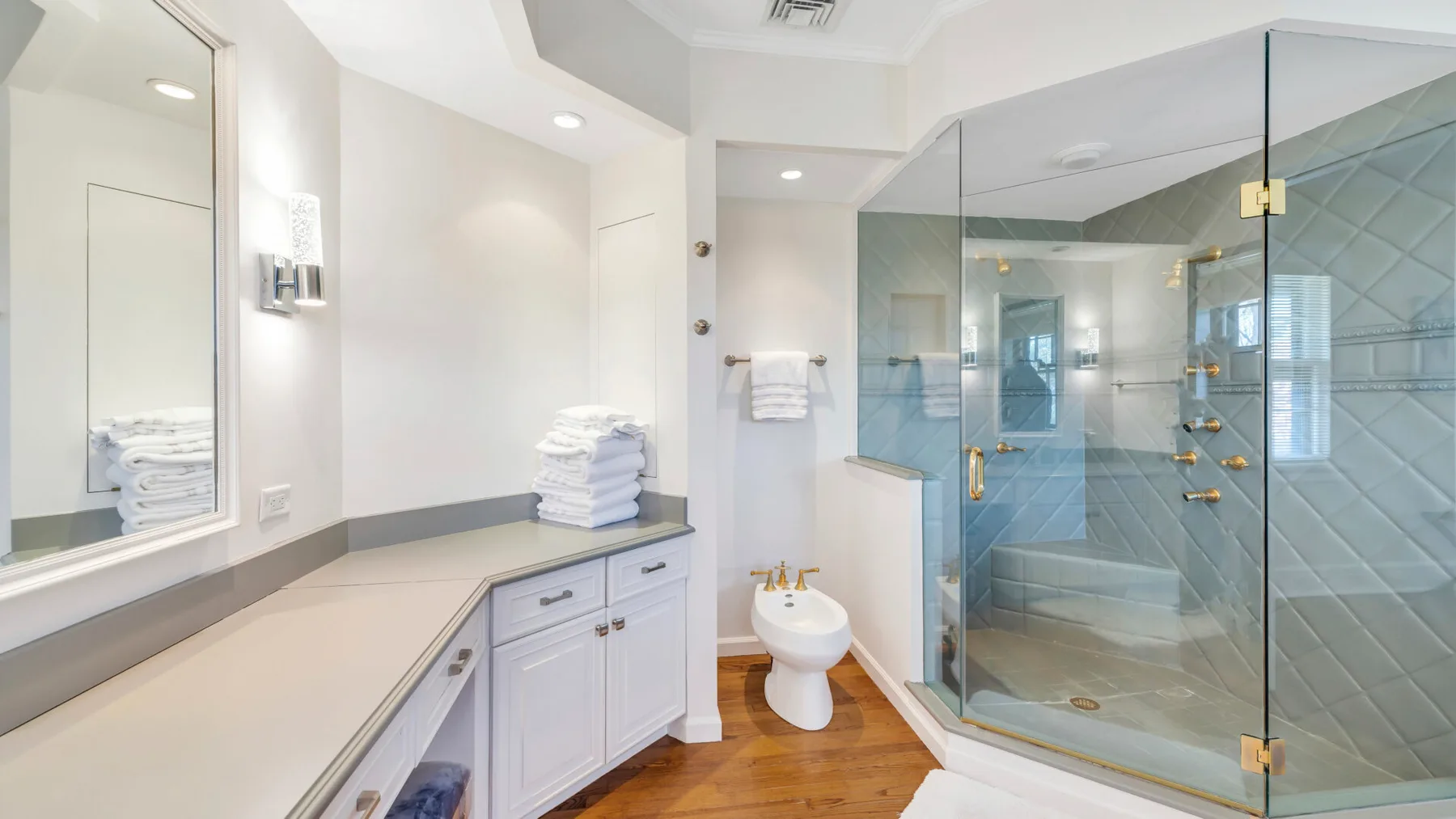 Un baño luminoso con un tocador largo y una ducha con mampara de vidrio.
