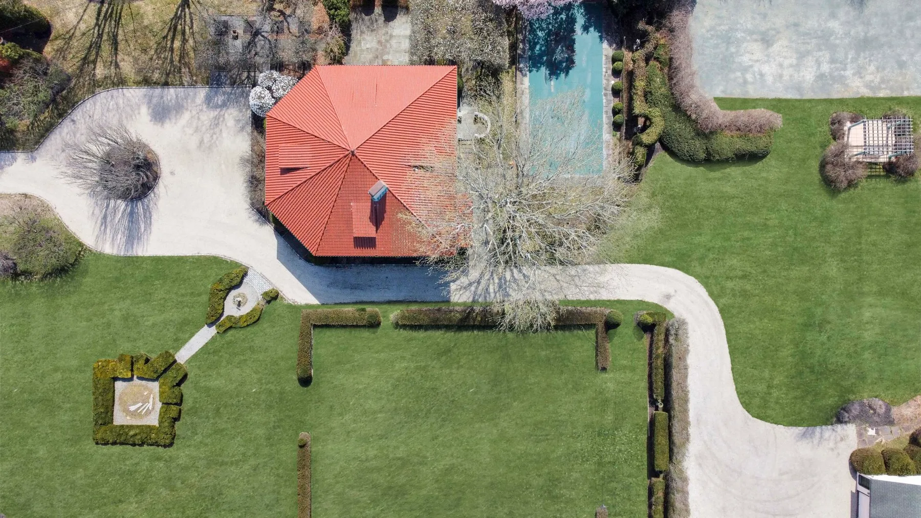 Una vista aérea muestra un jardín con una casa, caminos y una piscina.