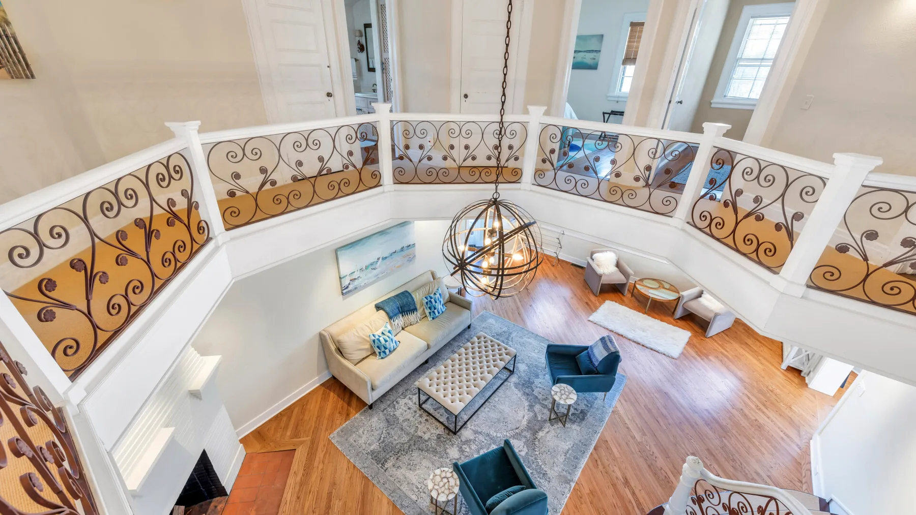 Una luminosa sala de estar de dos niveles con una zona de asientos bajo un balcón decorativo.