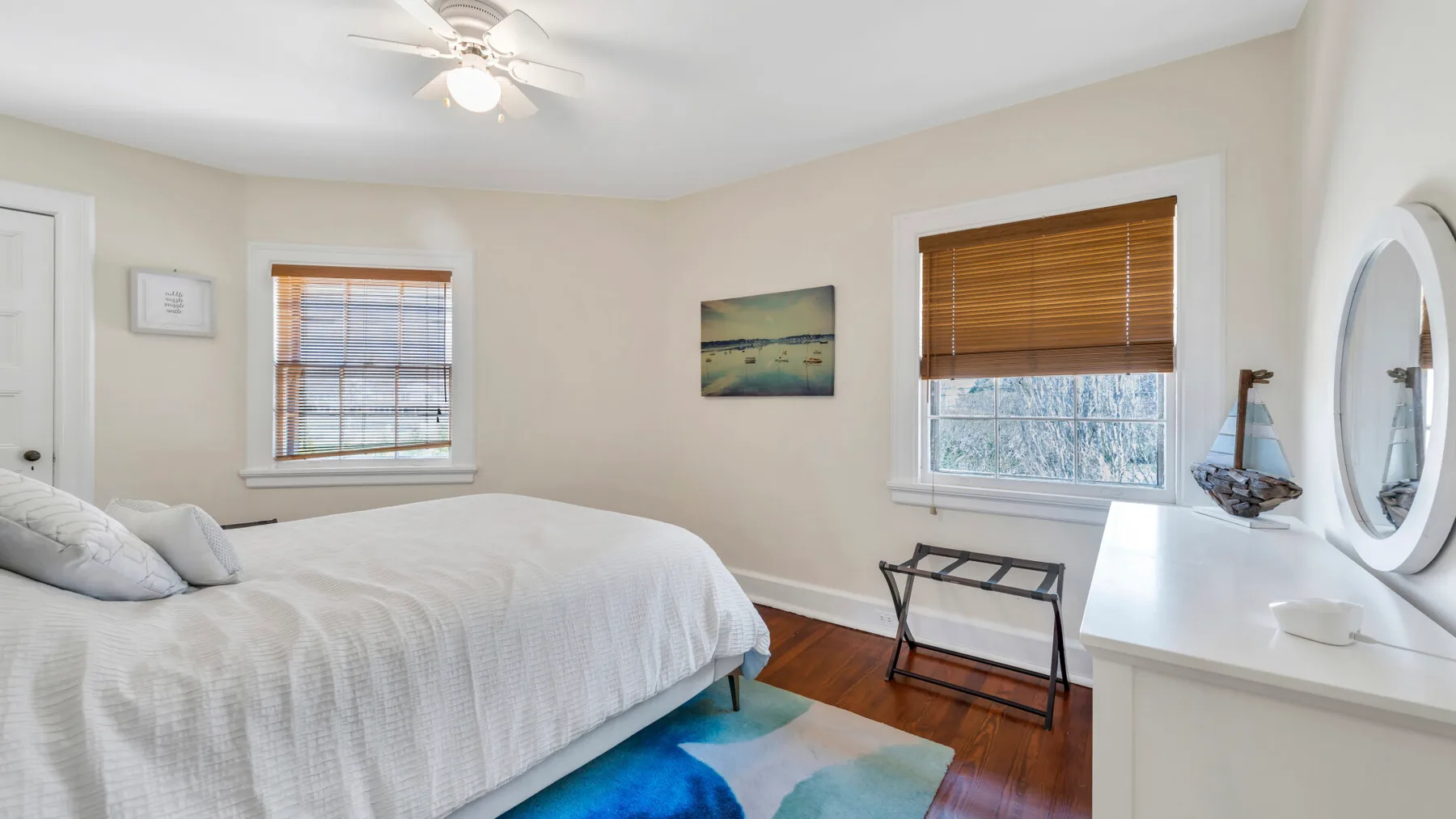 Un dormitorio con una cama, dos ventanas y un tocador blanco.