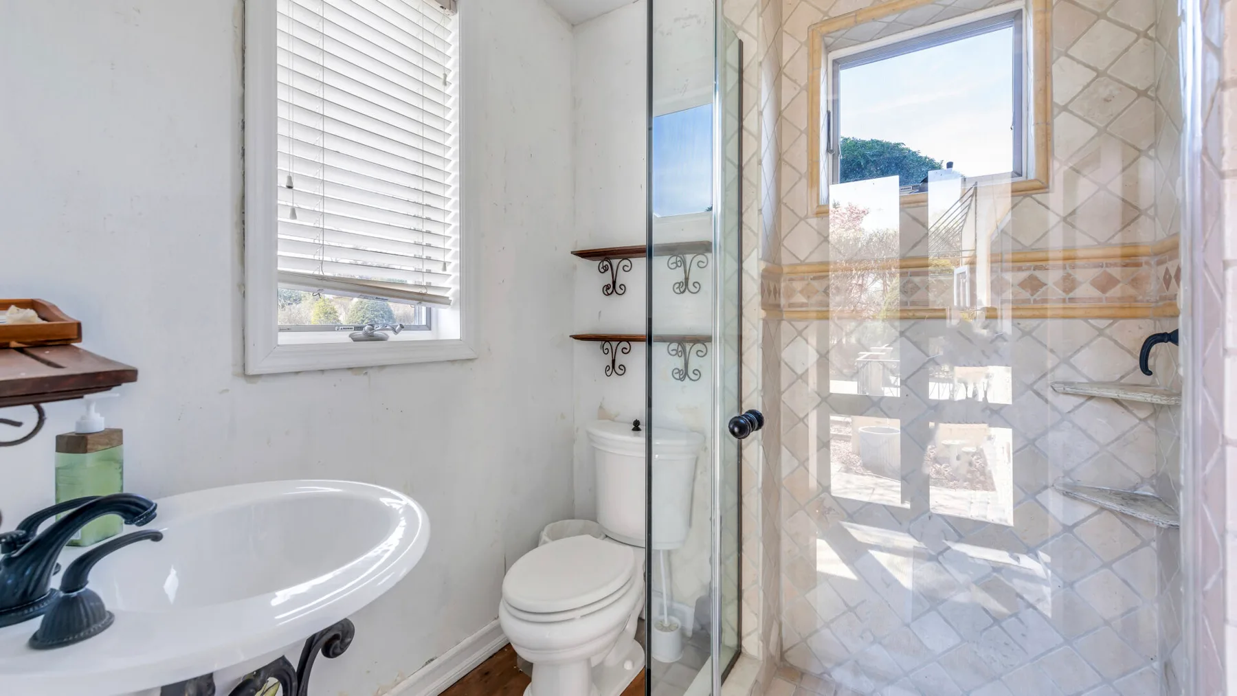 Un baño luminoso con lavabo, inodoro y ducha de cristal.
