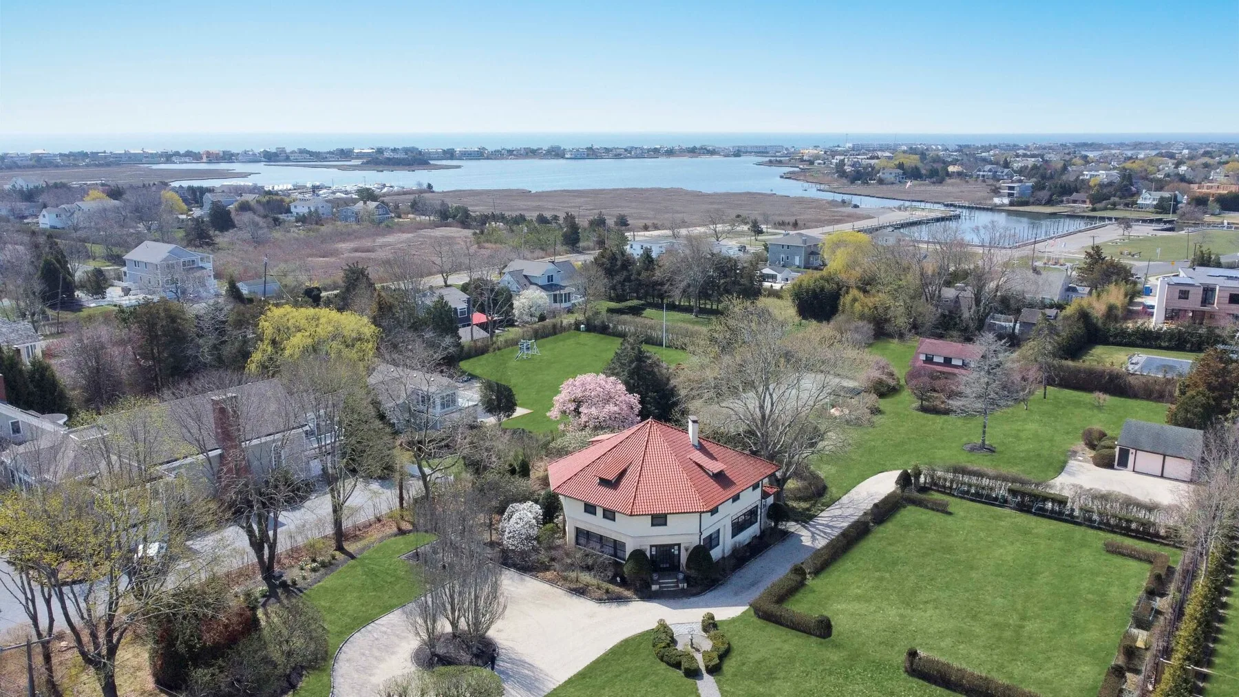 Aerial view of a landscaped residential property beside a broad waterway.