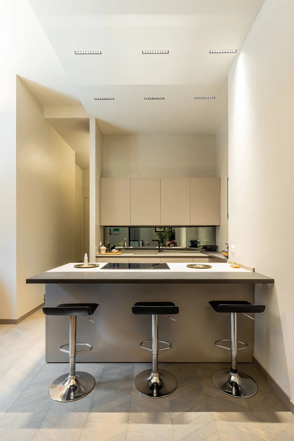 Una cocina luminosa con una isla y tres taburetes de bar.