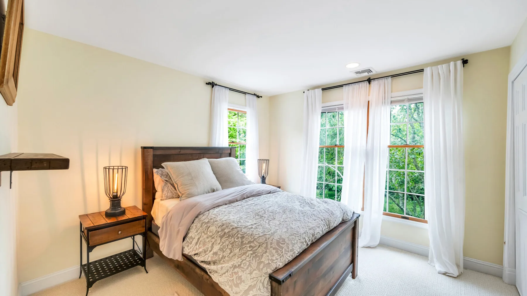 Un dormitorio luminoso con una cama de madera vestida con ropa de cama clara.