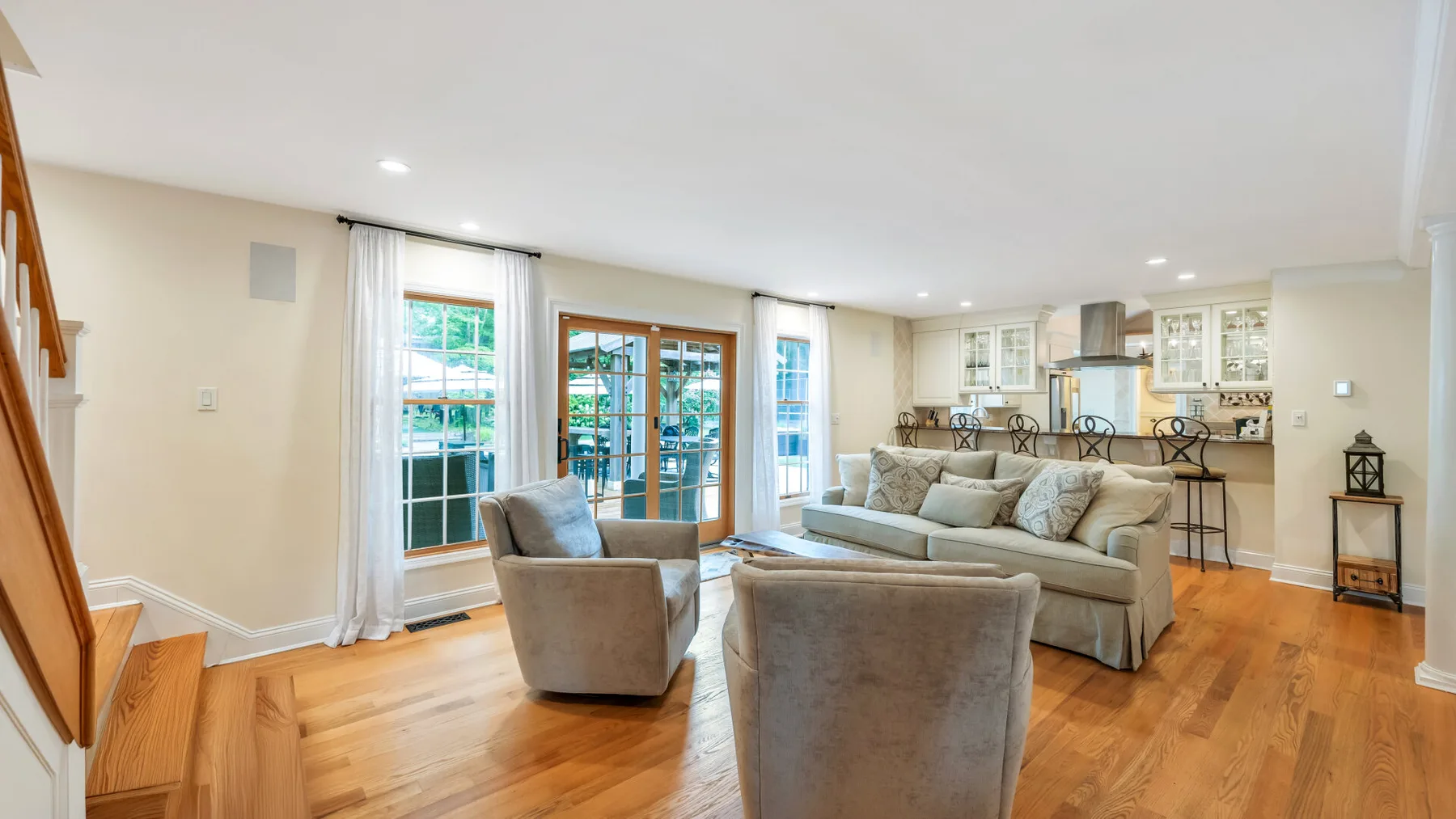 Una sala de estar con asientos junto a grandes ventanas y una cocina abierta.