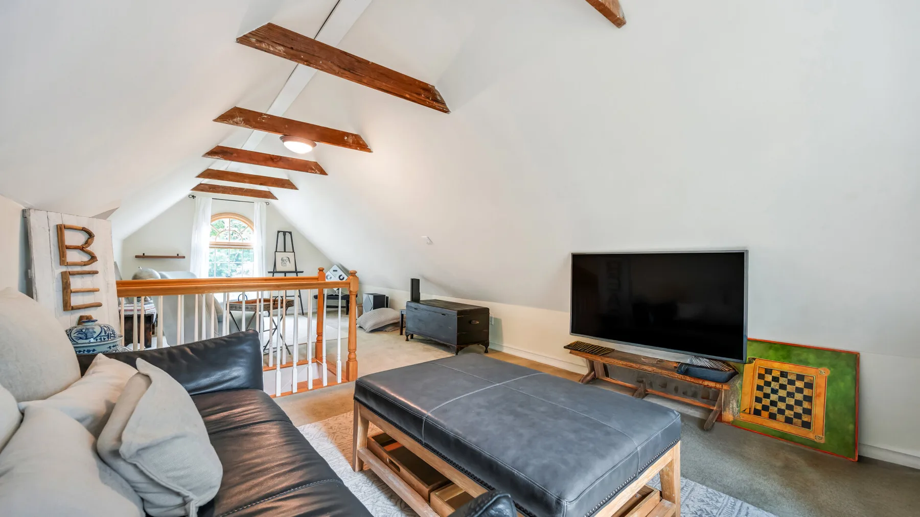 Una luminosa sala tipo loft con un gran reposapiés y televisor.
