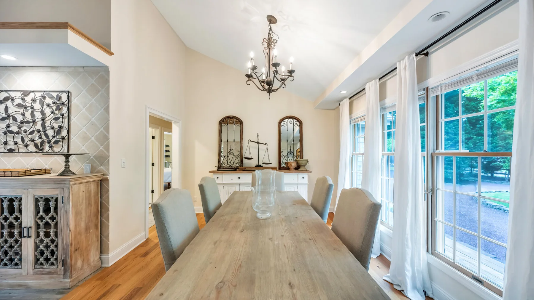 Un comedor luminoso con una mesa larga de madera junto a grandes ventanas.
