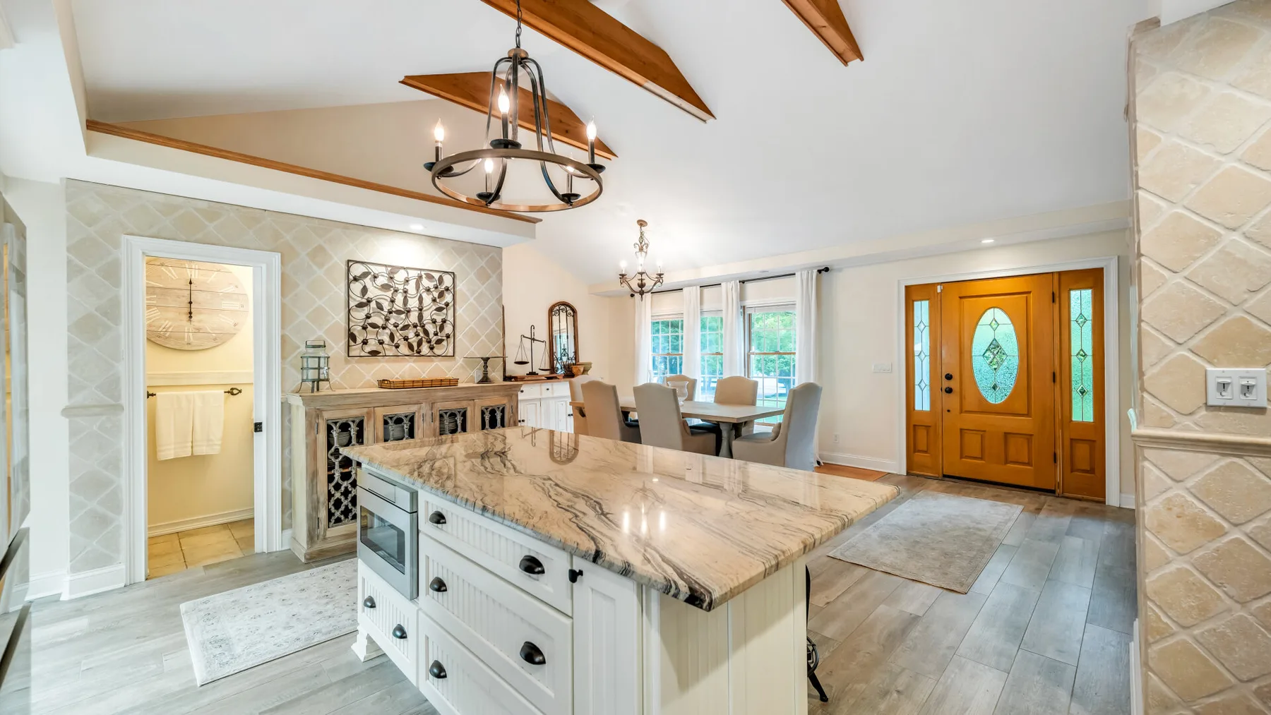 Cocina y comedor abiertos con una isla grande y puertas de entrada de madera.