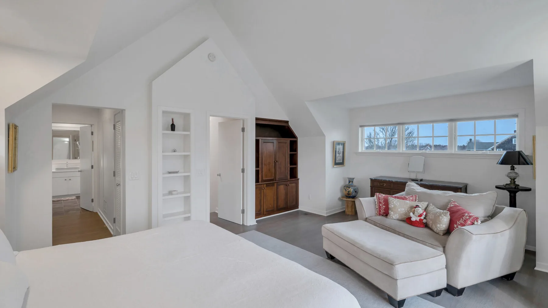 Un dormitorio luminoso con una cama grande y una zona de estar junto a la ventana.