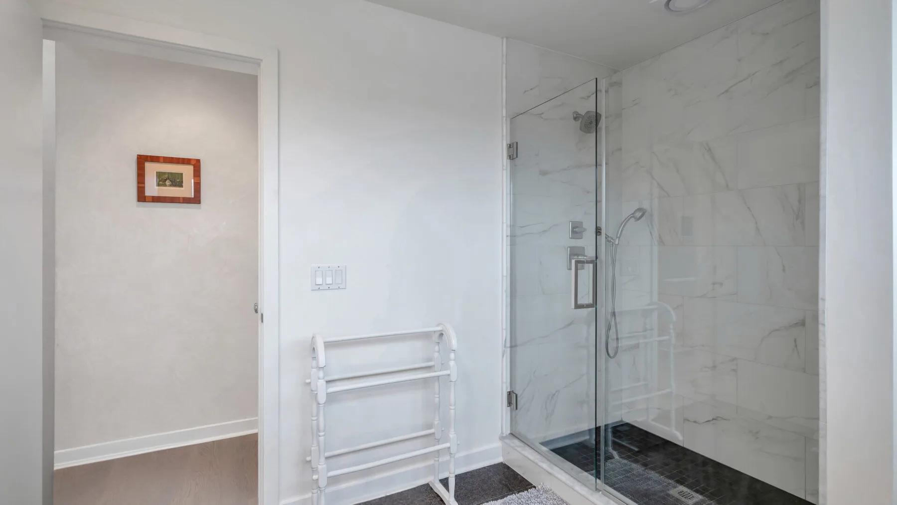 Un baño con una ducha de vidrio y paredes revestidas de azulejos blancos.