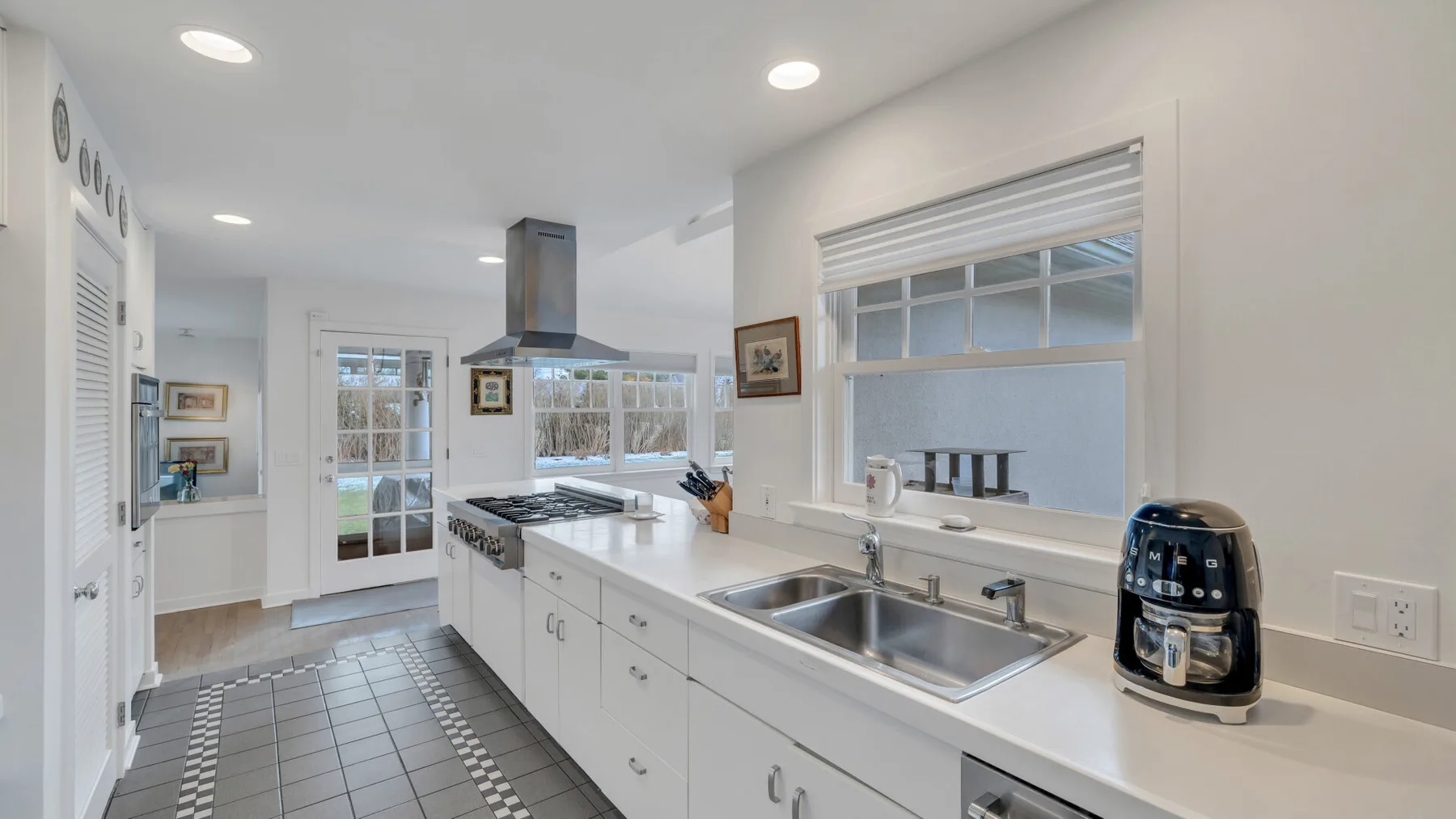 Una cocina luminosa con una isla larga, fregadero y ventanas grandes.